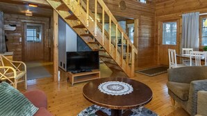 A wooden cabin interior with a staircase, a television, a dining area, and a cozy seating arrangement. - Saarijärvi by Interhome (Sulkava)