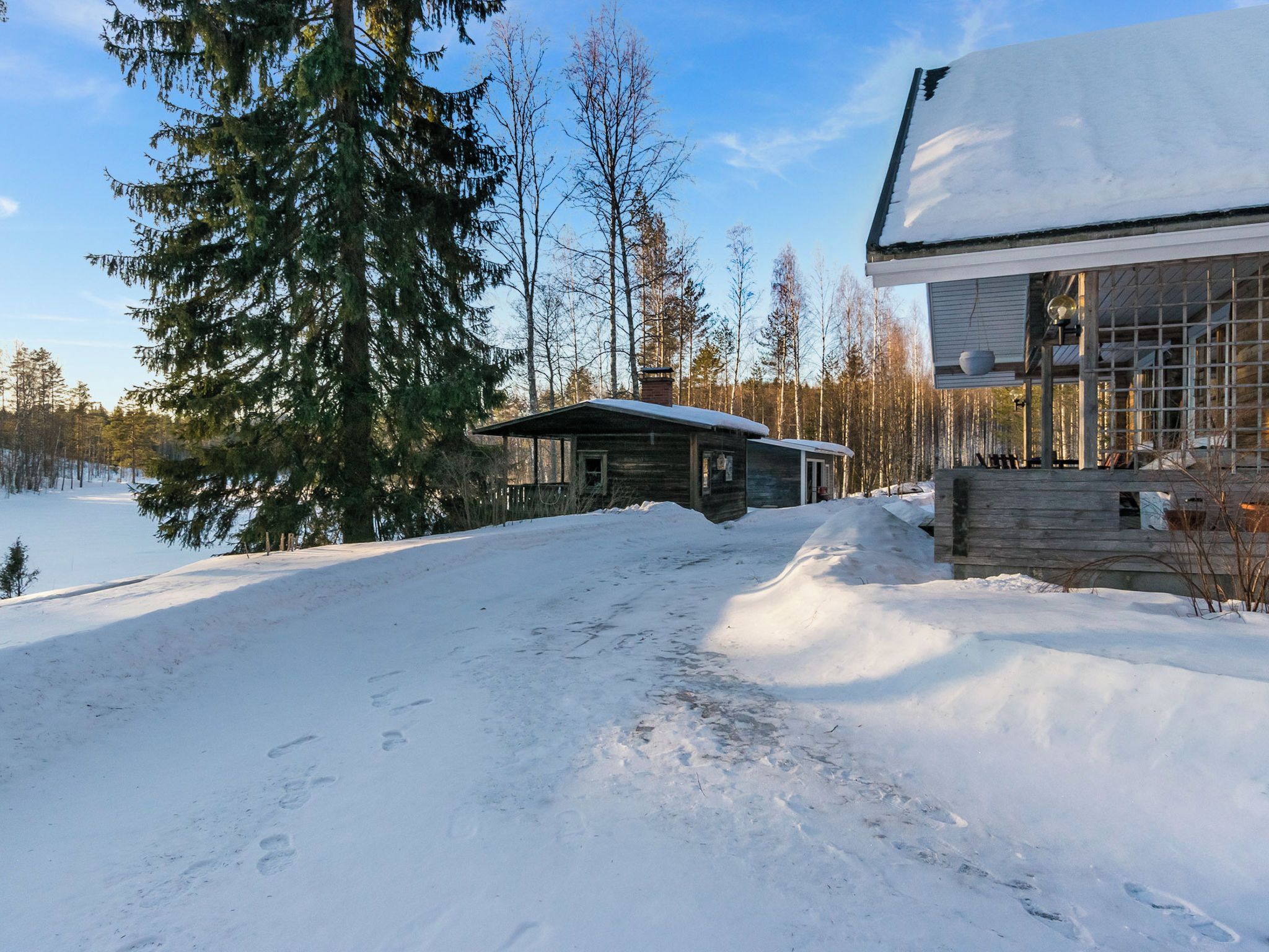 Een chalet met een met sneeuw bedekte dak, omgeven door een bos en een meer.