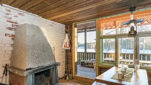 A rustic cabin interior with a stone fireplace, wooden deck, and large windows overlooking a snowy landscape. - Saarijärvi by Interhome (Sulkava)