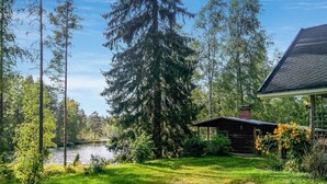 A cabin with a pond, surrounded by tall trees and a clear sky. - Saarijärvi by Interhome (Sulkava)