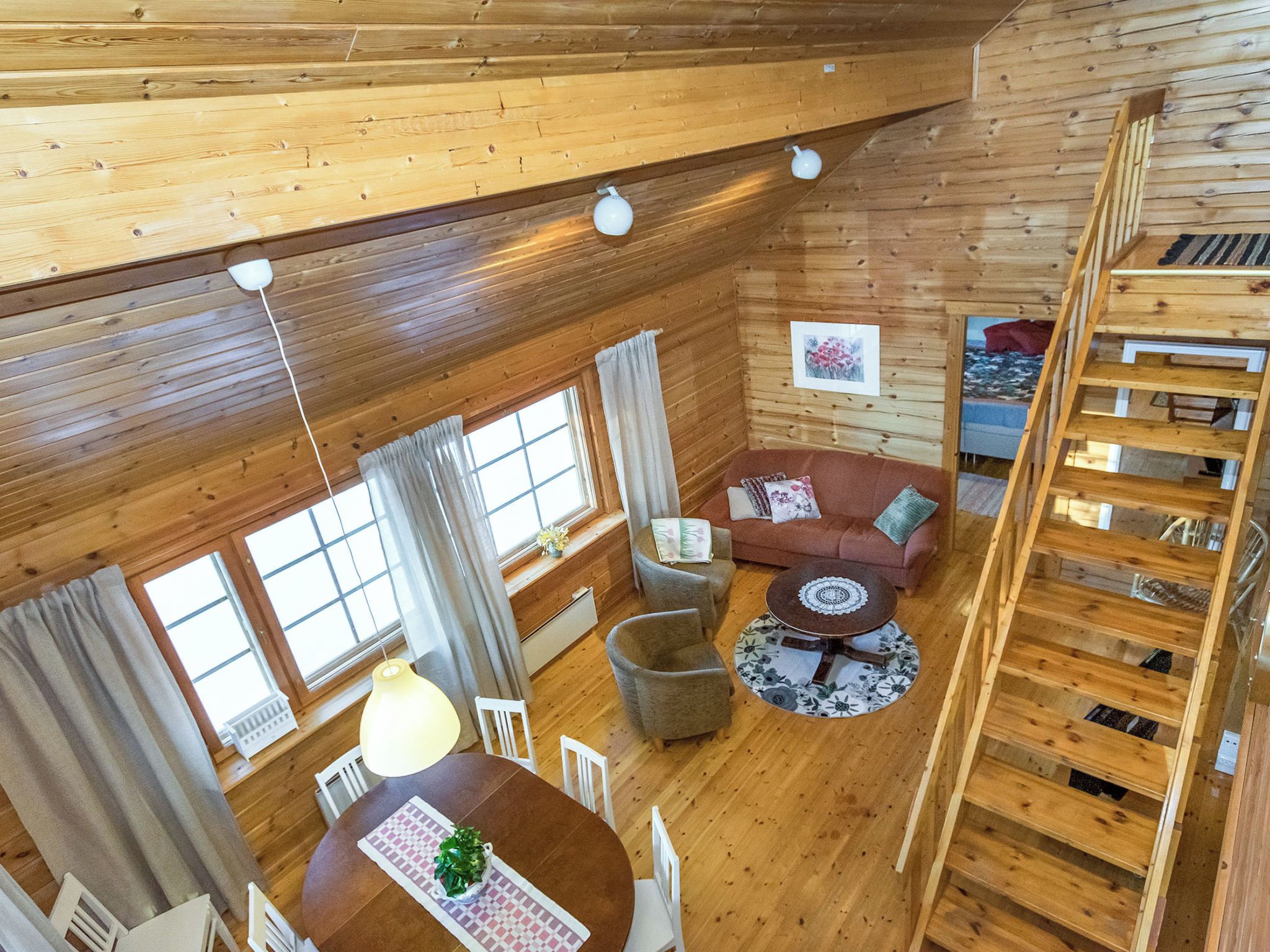 En interiör med träinredning, ett matområde, en soffa och en trappa.