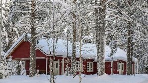 Uma cabana vermelha rodeada por árvores cobertas de neve.