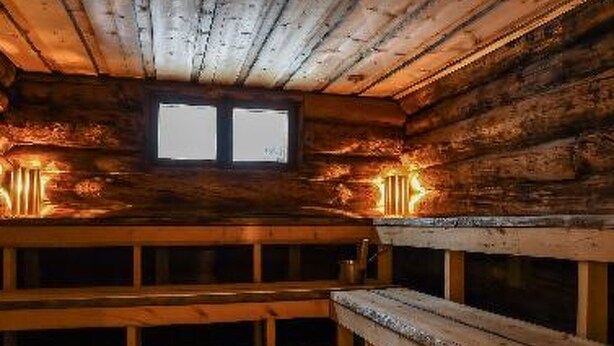 Interior de uma cabana de madeira com um banco e uma janela.