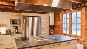Cozinha moderna com eletrodomésticos de aço inoxidável, armários de madeira e uma janela ampla que oferece iluminação natural.