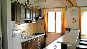 Una cocina con armarios de madera, estufa, lavaplatos y una barra con taburetes.