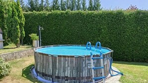 Una piscina elevada de madera con una escalera y una piscina infantil azul.