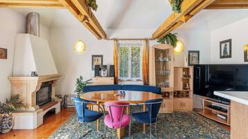 Un salon chaleureux avec une cheminée, une table à manger ronde entourée de chaises, un téléviseur et une bibliothèque.