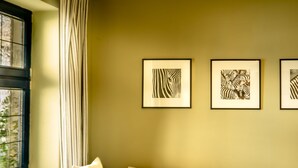 A room with a window, a sofa with cushions, and three framed artworks on the wall. - Apartment Wagner by Interhome (Marianske Lazne)