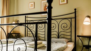 A bed with a metal frame and a patterned bedspread, a bedside table with a lamp, and framed artwork on the wall. - Apartment Wagner by Interhome (Marianske Lazne)
