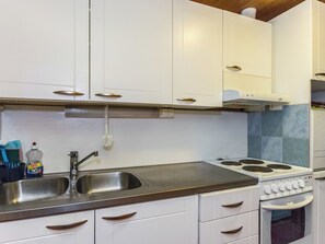 A kitchen with white cabinets, a stainless steel sink, and a stove. - Iltarusko by Interhome (Punkaharju)