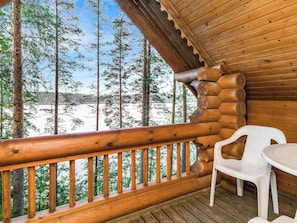 A wooden cabin with a balcony overlooking a snowy landscape.