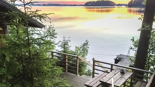 A wooden deck with benches overlooking a calm lake at sunset.