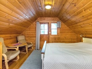 A cozy attic bedroom with a wooden sloped ceiling, a single bed, a desk with a chair, and a window with curtains. - Iltarusko by Interhome (Punkaharju)