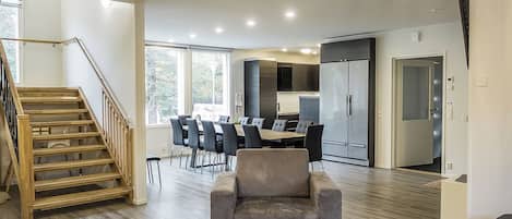 Un interior moderno con una escalera, comedor, cocina y zona de estar.