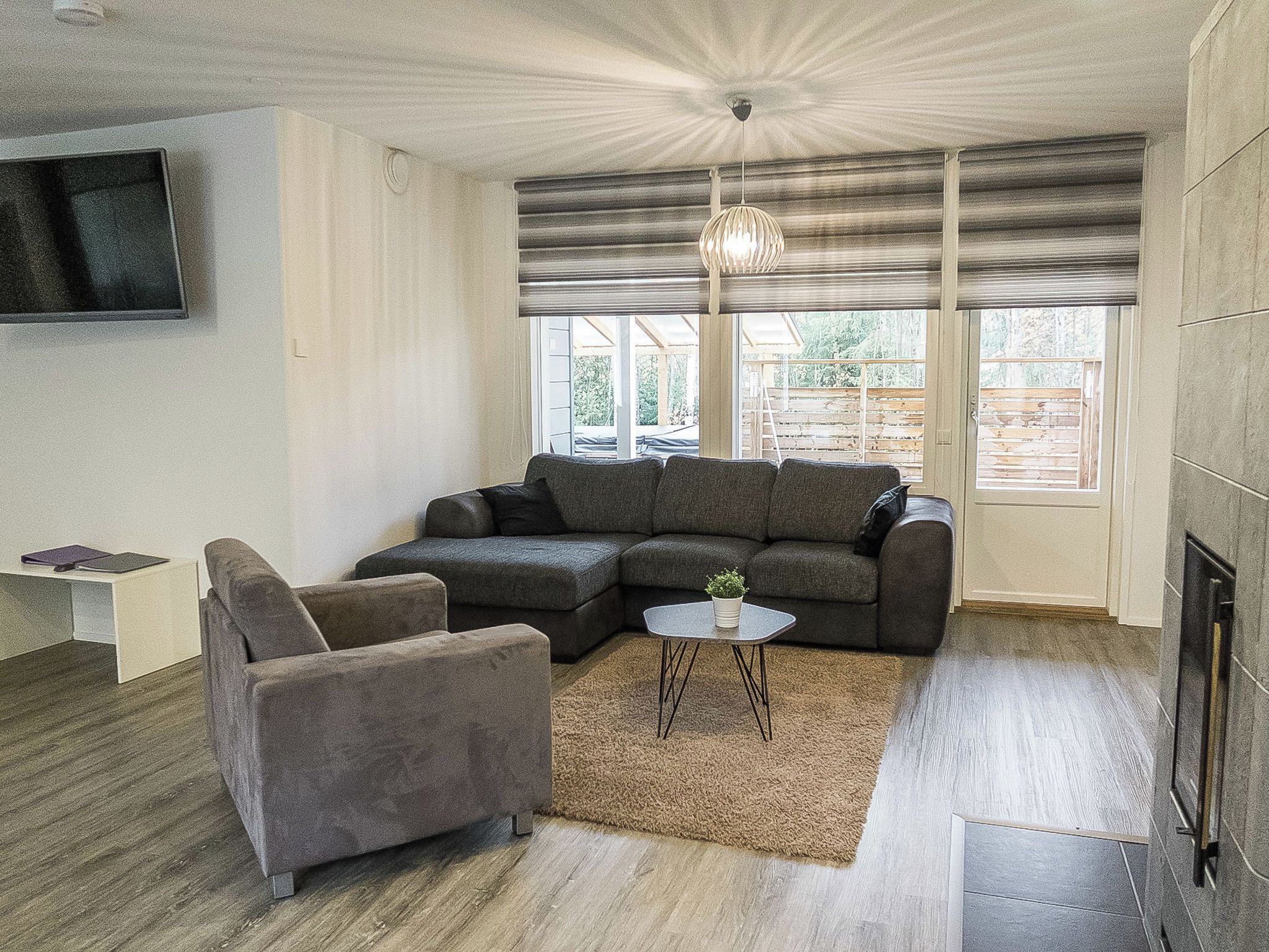 Un salon moderne avec un canapé d’angle, une petite table d’appoint et une cheminée.