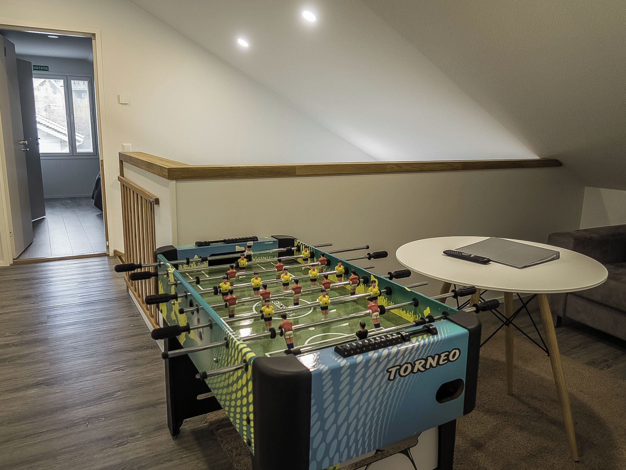 A foosball table in a room with a small round table and a sofa.