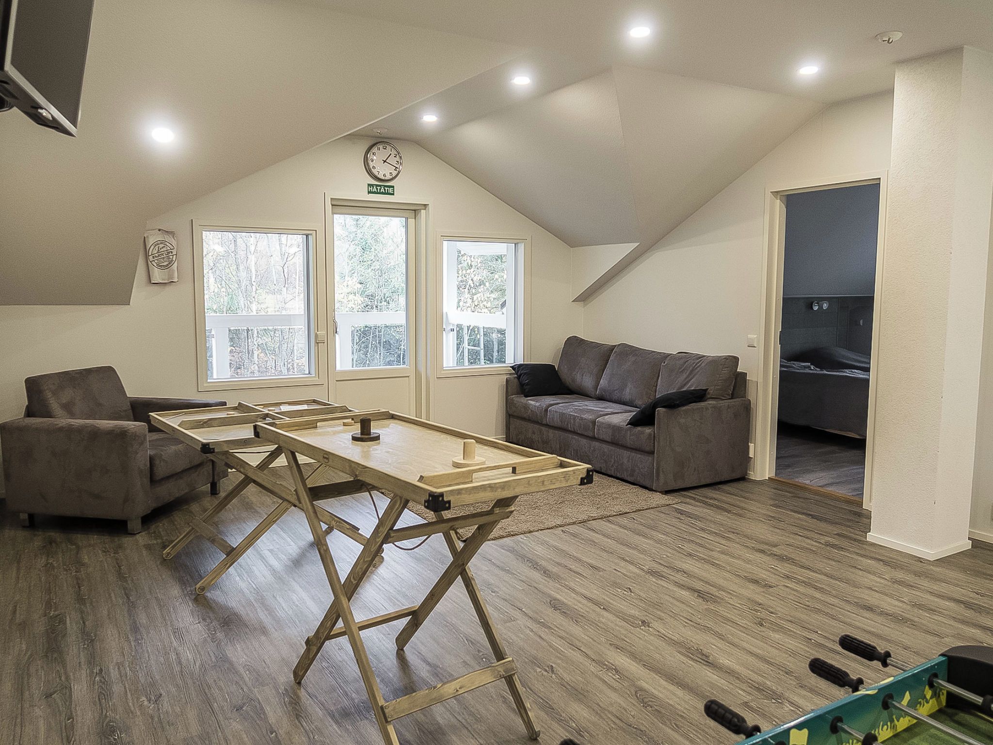 Avoin, loft-tyylinen huone, jossa on puinen pöytä, kaksi sohvaa ja näkymä parvekkeelle.
