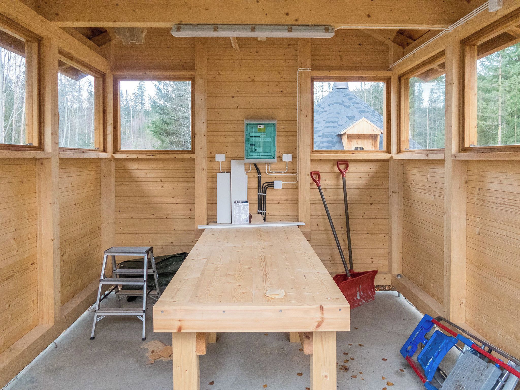 Un intérieur en bois avec une table, une échelle et un coffre à outils.