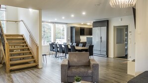 A modern kitchen with a dining area, a staircase, and a living room with a sofa and coffee table.