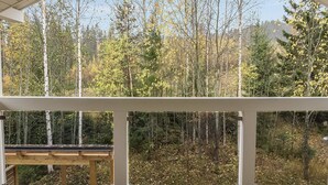 A covered outdoor deck with a view of a forested area.