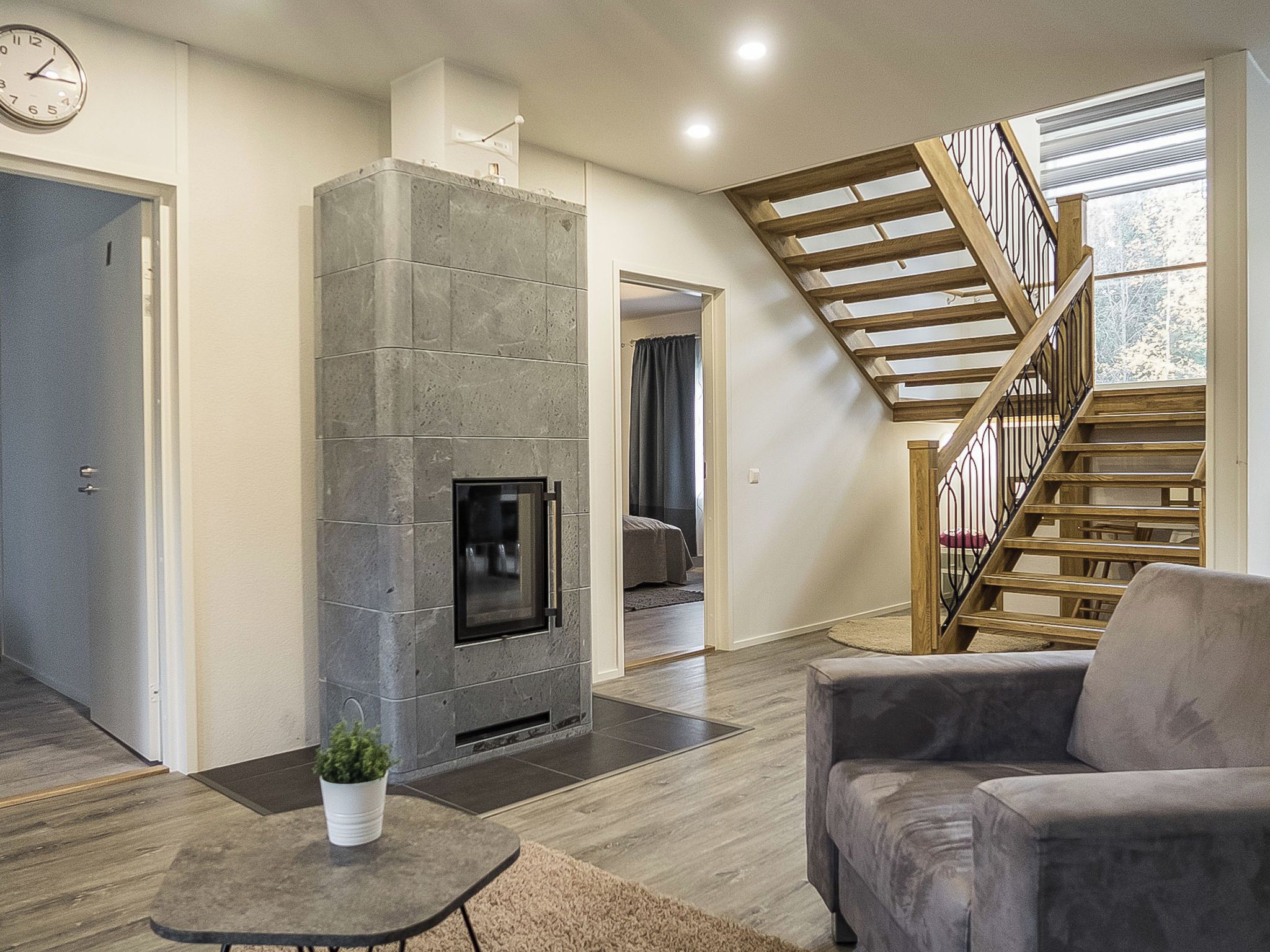 Ein modernes Wohnzimmer mit Kamin aus Stein, einer Wendeltreppe und Blick ins Freie.