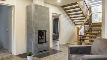 Ein modernes Wohnzimmer mit Kamin aus Stein, einer Wendeltreppe und Blick ins Freie.