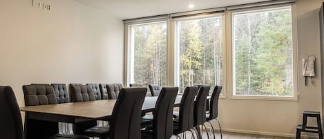 Ein Konferenzraum mit einem langen Tisch und Stühlen, großen Fenstern mit Blick auf Bäume und einem hellen Boden.