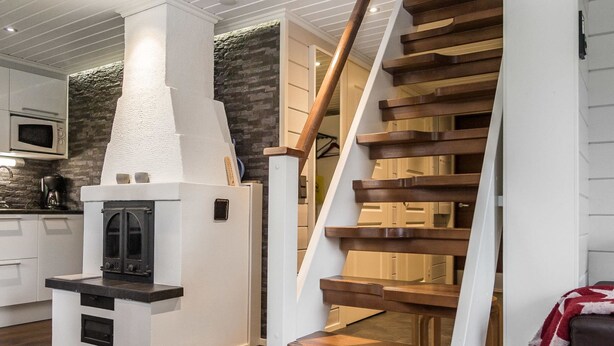 Een moderne keuken met een inbouwoven, een houten trap en een accentmuur van steen.