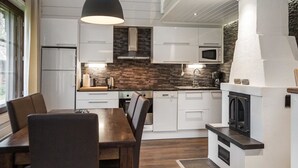 Een moderne keuken met witte kastjes, een betegelde spatwand, een ingebouwde oven en een eethoek met een houten tafel en stoelen.