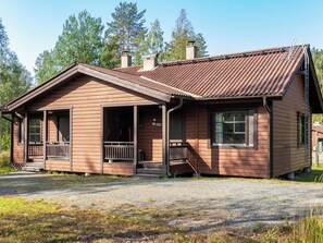 Une cabane en bois avec un porche, une cheminée et une allée gravillonnée.
