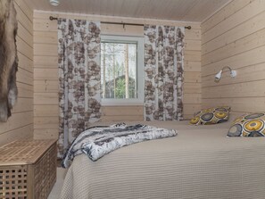 Ein Schlafzimmer mit Bett, Vorhängen, einem Fenster und einer Lampe.