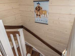 A wooden interior with a poster featuring a reindeer and a man, and a white chair. - Äkäsmartti a by Interhome (Äkäslompolo)