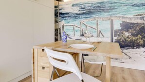 A dining area with a wooden table, white chairs, and a coastal mural on the wall. - Sun Beach by Interhome (Arcachon)