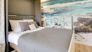 A bedroom with a bed, a headboard, and a mural of a beach scene. - Sun Beach by Interhome (Arcachon)