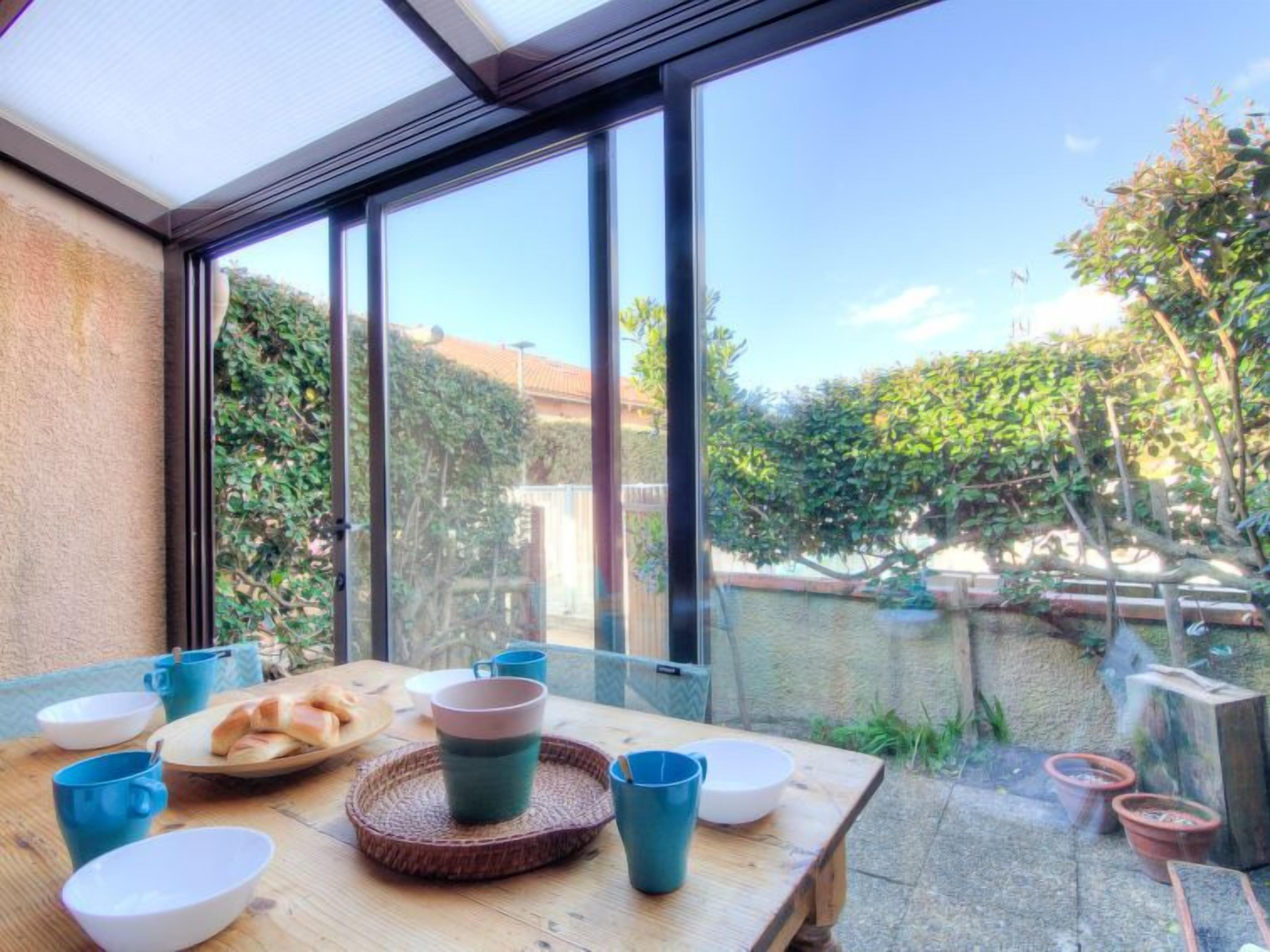 A dining area with a table set for two, featuring a plate of bread, a cup, and a bowl.