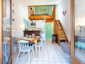 A compact living space with a dining area, kitchen, and a loft bedroom.