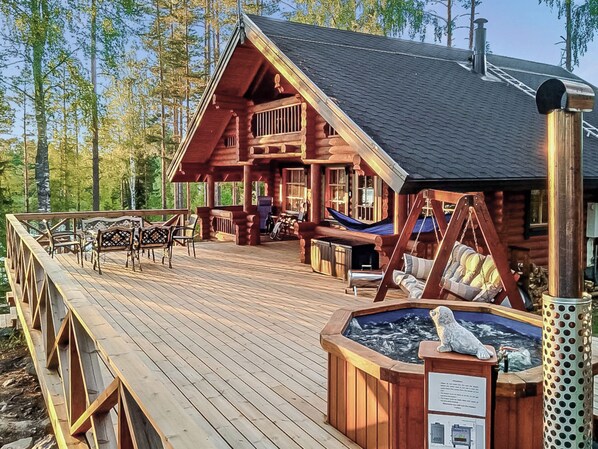A log cabin with a deck, outdoor seating, and a hot tub. - Erätorsa by Interhome (Rautjärvi)