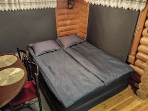 A small, cozy room with a bed, a chair, and a table.