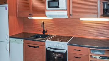 Une cuisine compacte dotée de meubles en bois, d’un four à micro-ondes, d’une cuisinière et d’un lave-vaisselle.