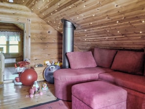 A cozy cabin interior with a wooden ceiling, a red sofa, and various children's toys on the floor. - Erätorsa by Interhome (Rautjärvi)