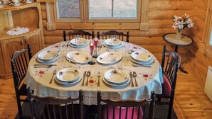 A wooden interior with a round dining table set for six, surrounded by chairs with cushioned seats. - Erätorsa by Interhome (Rautjärvi)