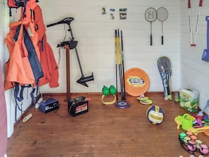 A room with a wooden floor, a bicycle, a badminton racket, a volleyball, and various sports equipment.