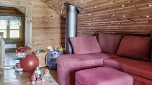 A cozy room with a wooden ceiling, a red sofa, and various children's toys on the floor. - Erätorsa by Interhome (Rautjärvi)