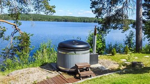En transportabel grill med skorsten, en træbænk og en belagt sti ved en sø.