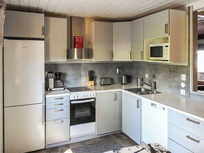 A compact kitchen with a refrigerator, stove, microwave, and sink.