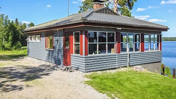 Pieni, yhden kerroksen rakennus, jossa on kalteva katto, suuret ikkunat ja ovi.