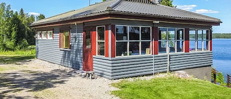 En liten, envåningsbyggnad med ett sluttande tak, stora fönster och en dörr.