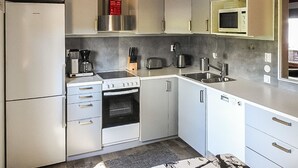 Et lille køkken med køleskab, komfur, mikrobølgeovn og vask.