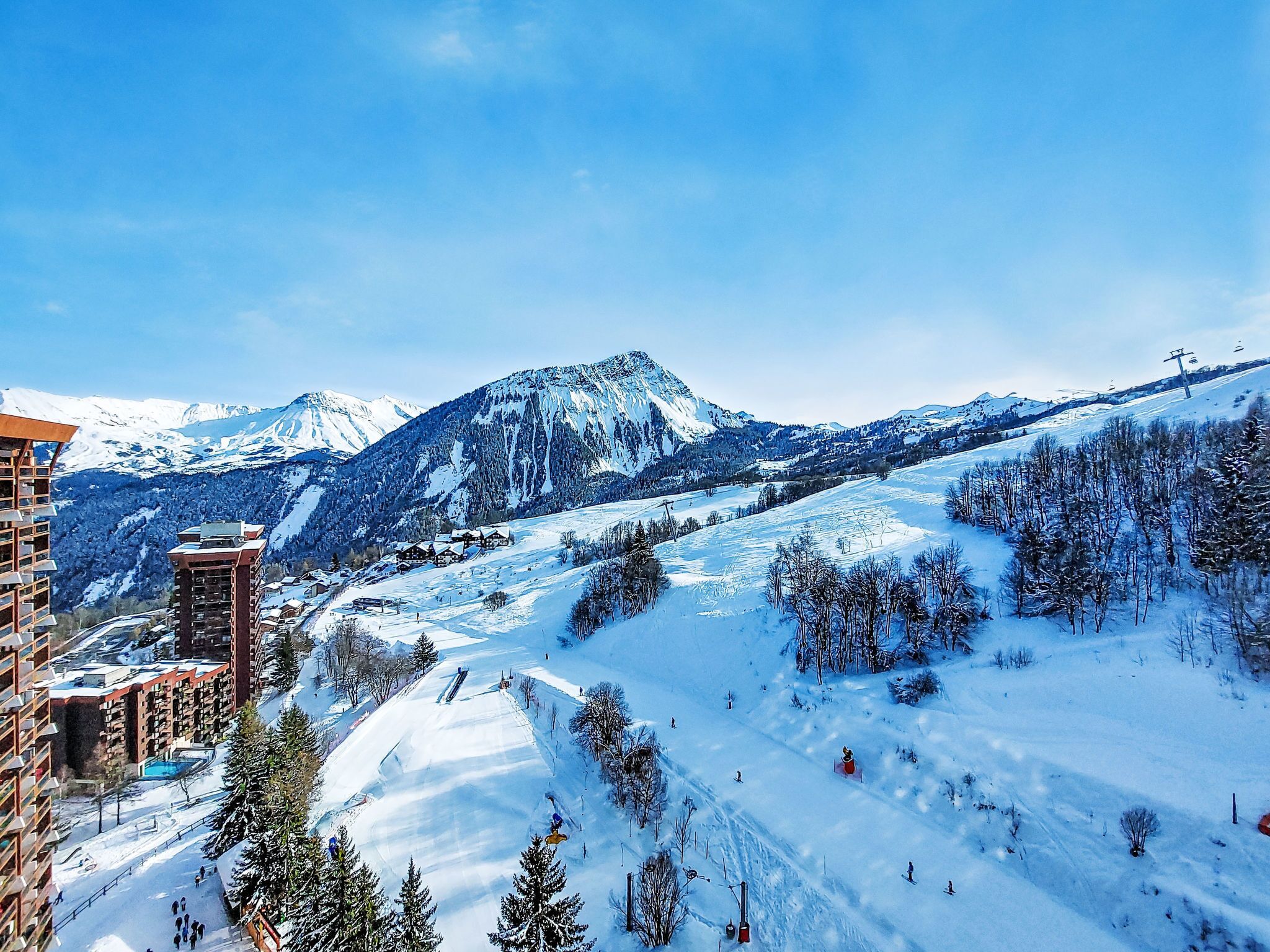 A snow-covered mountain landscape with a ski resort, including ski lifts and buildings.