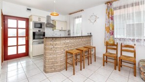 A kitchen with a central island, wooden chairs, and a dining table. - Yellow 1 by Interhome (Balatonmariafurdo)